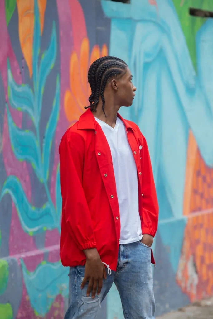 Male model in red jacket and white shirt standing against colorful street mural backdrop