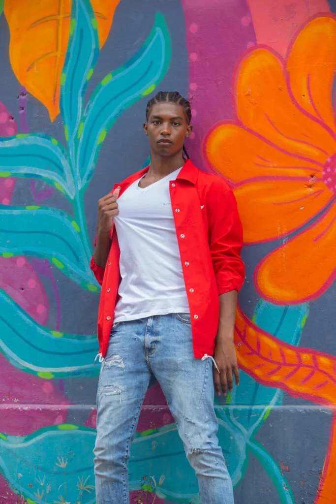 Male model in red jacket and white shirt against vibrant colorful floral mural