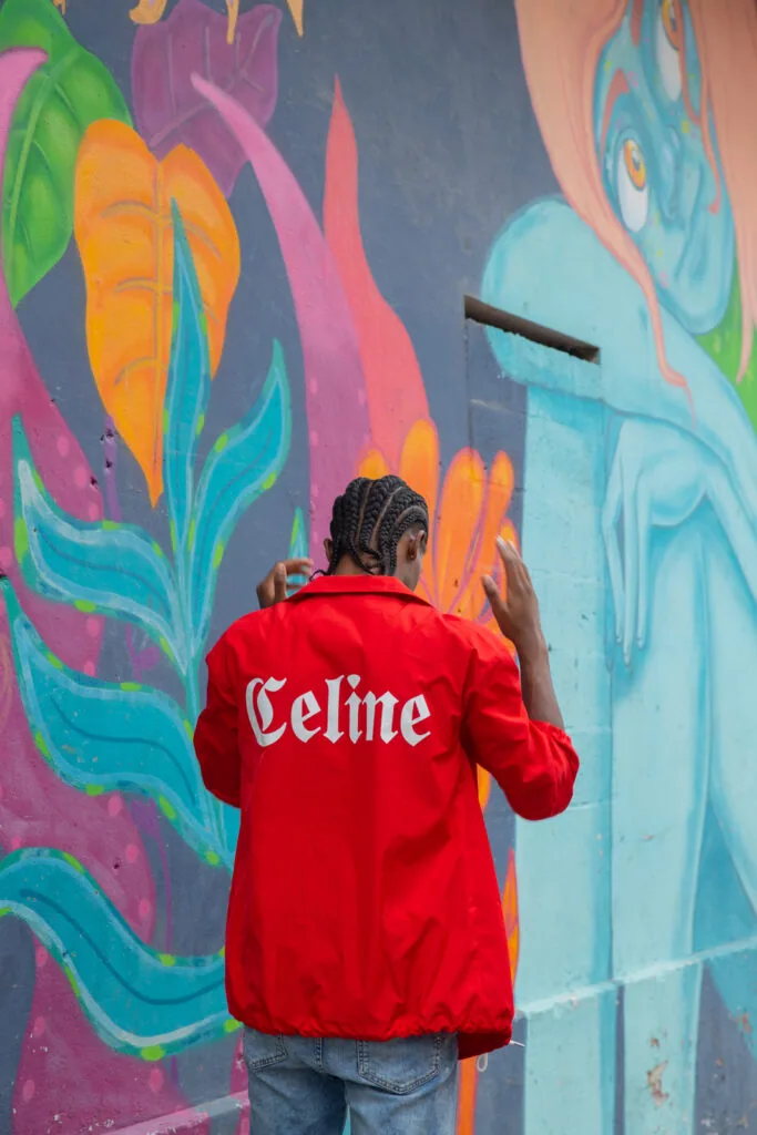 Man in red jacket facing colorful floral mural with orange, pink, and blue flowers