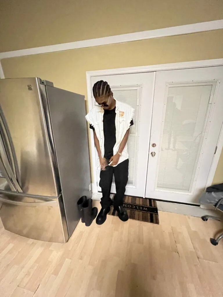 Male model in white shirt and black pants standing in modern kitchen with stainless steel appliances and white doors