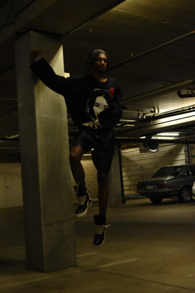 Male model jumping in graphic t-shirt and shorts in concrete parking garage with support column