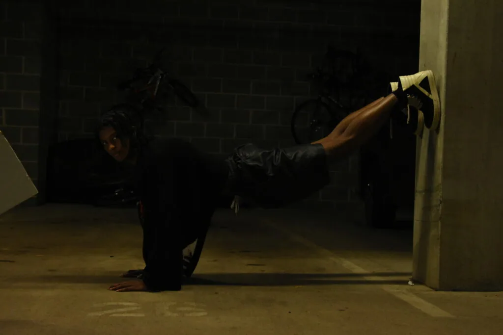 Male model in black leather jacket performing dynamic pose against concrete wall in gallery space