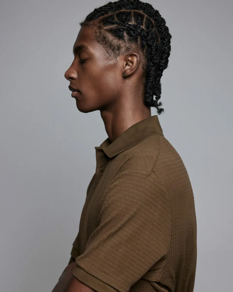 Male model in profile wearing olive braided polo shirt against gray background