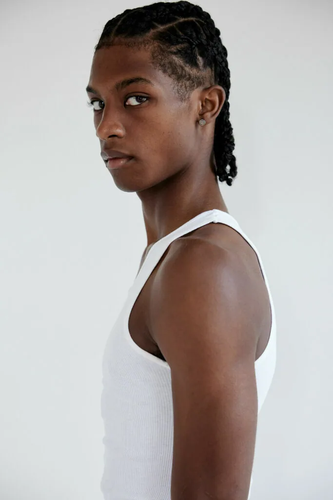Male model in white sleeveless tank top, side profile pose against neutral background