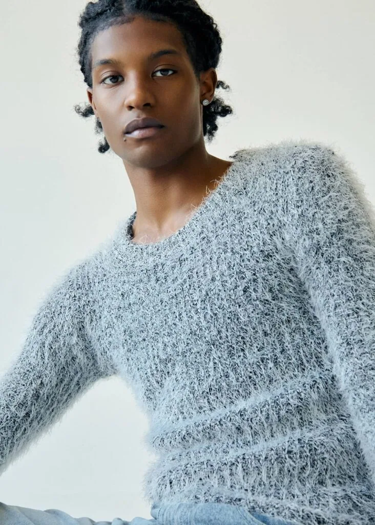Person wearing a textured light gray sweater against a neutral background