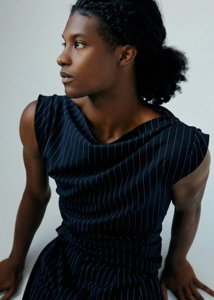 Person wearing dark pinstriped sleeveless top, shown in profile against light background